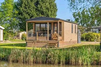 a tiny house sitting on the side of a lake at Camping Papillon Kinrooi - Vakantiehuis Premium 4P in Kinrooi