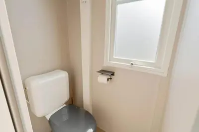 a small bathroom with a toilet and a window at Camping Papillon Kinrooi - Vakantiehuis Premium 4P in Kinrooi