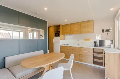 a kitchen with a wooden table and white chairs at Camping Papillon Kinrooi - Vakantiehuis Premium 4P in Kinrooi