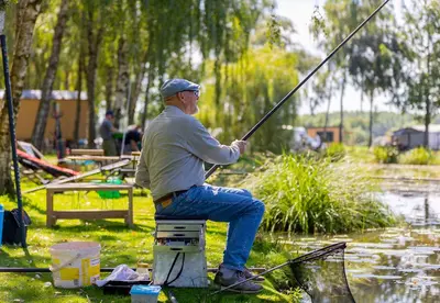 a man sitting on a block holding a fishing pole at Camping Papillon Kinrooi - 86 in Kinrooi