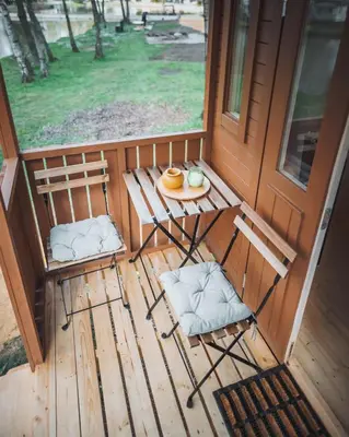 a porch with two chairs and a table with a plate of food at Camping Papillon Kinrooi - Pipowagen 2p terras in Kinrooi