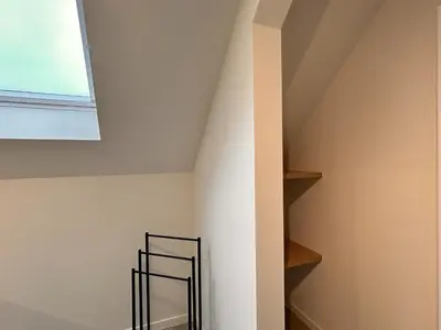 a stair case in a attic with a window at Spacious 3-Floor Holiday Home for 8 Guests in Bree