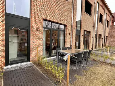 a table and chairs in front of a brick building at Spacious 3-Floor Holiday Home for 8 Guests in Bree