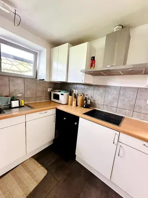 a kitchen with white cabinets and a sink and a window at Dukes View -explore Haspengouw & surrounding towns in Zoutleeuw