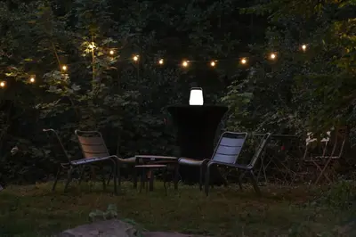 three chairs and a lamp in a garden at night at Homestorys Nature Resort - Wood Lounge in Eupen