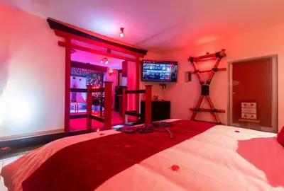 a bedroom with a large bed with pink lighting at Temple Torii in Crisnée