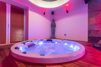 a hot tub in a room with pink lighting at Temple Torii in Crisnée