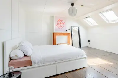 a white bedroom with a large bed in a room with windows at L'appartement Casquette in Liège