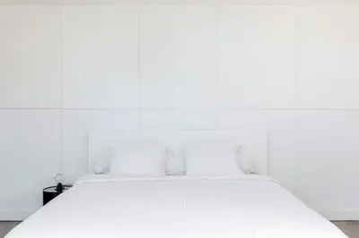 a white bed in a room with a white wall at L'appartement Casquette in Liège