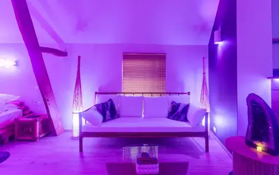 a living room with a white couch in a purple room at L'Améthyste in Crisnée