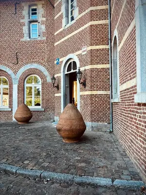two large vases sitting outside of a brick building at 'T Rood Kasteel in Hasselt