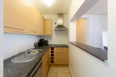 a kitchen with a sink and wooden cabinets at Moni 2G Residence in Seraing