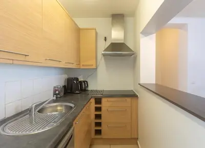 a kitchen with a sink and wooden cabinets at Moni 2G Residence in Seraing