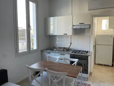 a kitchen with a wooden table and white cabinets at chez zakk in Seraing