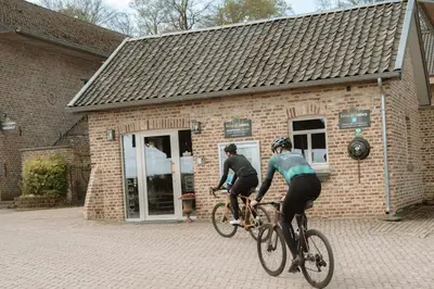 two people riding bikes in front of a brick building at Camping Natuurlijk Limburg - Appartement 6p in Voeren