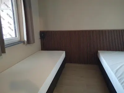 a small room with two beds and a window at Camping Natuurlijk Limburg - Appartement 6p in Voeren