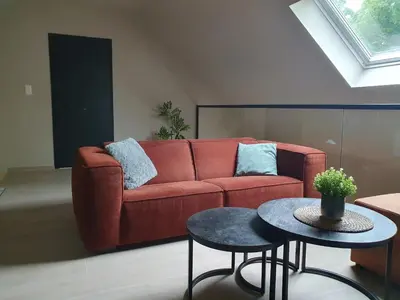 a living room with a red couch and a table at Camping Natuurlijk Limburg - Appartement 6p in Voeren