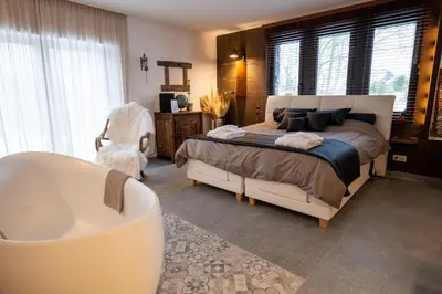 a bedroom with a bed and a bath tub at les jardins de la ferme in Soumagne