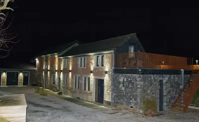 a large brick building with lights on it at night at les jardins de la ferme in Soumagne