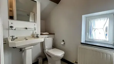 a bathroom with a toilet and a sink and a window at Hoefke Voort - Familievakantie midden in de natuur