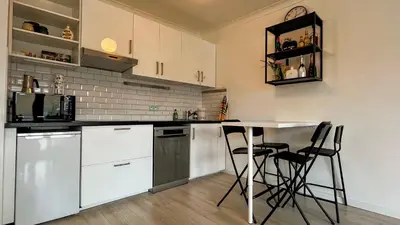 a kitchen with white cabinets and a table and chairs at Le Liégeois - Confort au Centre Ville in Liège