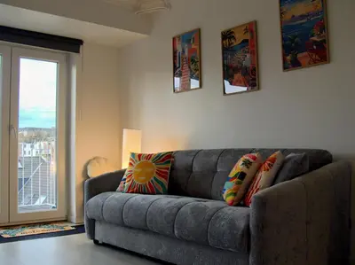 a living room with a gray couch with colorful pillows at Le Liégeois - Confort au Centre Ville in Liège