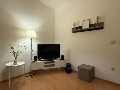 a living room with a television on a white desk at Duplexe Cosy - HERSTAL in Herstal