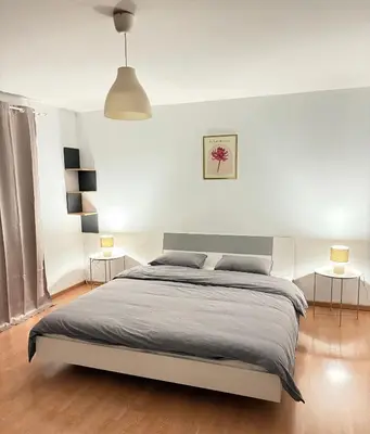 a white bedroom with a bed and two lamps at Duplexe Cosy - HERSTAL in Herstal