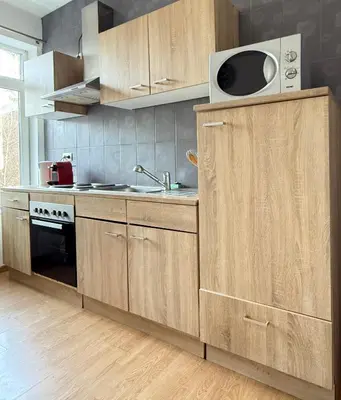 a kitchen with wooden cabinets and a sink and a microwave at Duplexe Cosy - HERSTAL in Herstal