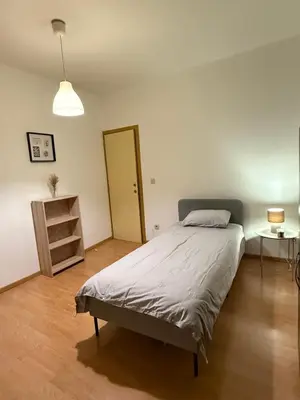 a bedroom with a bed and a table and a lamp at Duplexe Cosy - HERSTAL in Herstal