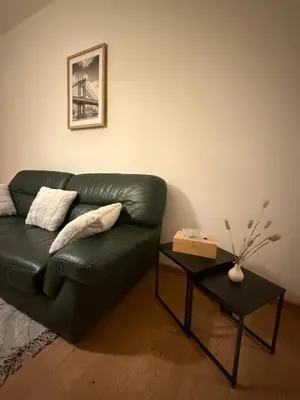 a living room with a green leather couch and a table at Duplexe Cosy - HERSTAL in Herstal