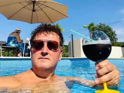 a man in a swimming pool holding a glass of wine at Villa a Chaudfontaine in Chaudfontaine