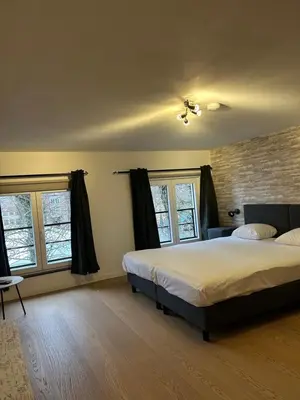 a bedroom with a large bed and two windows at Logies-Bistro Rosa in Maaseik