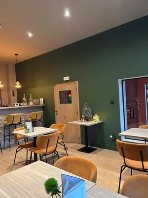 a restaurant with tables and chairs and a green wall at Logies-Bistro Rosa in Maaseik