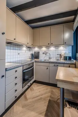 a kitchen with white cabinets and a wooden table at Lux Bos Chalet in Lanaken