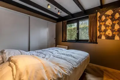 a bedroom with a large bed and a window at Lux Bos Chalet in Lanaken