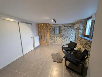 a living room with two chairs and a stone wall at Le Marie-Rose Charme et Pierre Porte des Fagnes in Baelen
