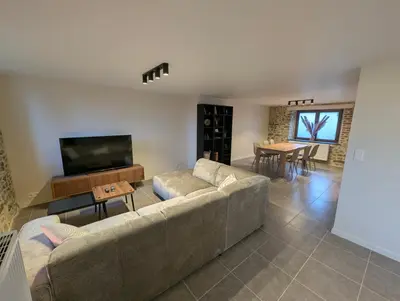 a living room with a couch and a television at Le Marie-Rose Charme et Pierre Porte des Fagnes in Baelen