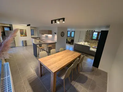 a kitchen and living room with a wooden table and chairs at Le Marie-Rose Charme et Pierre Porte des Fagnes in Baelen