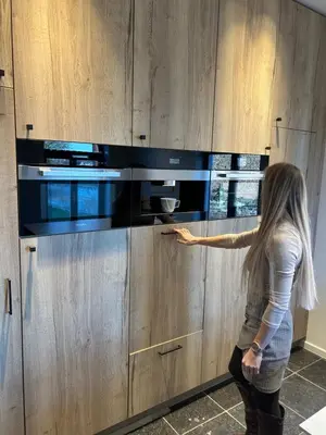 a woman is pointing at a microwave in a kitchen at Villa de Fraiture in Geetbets