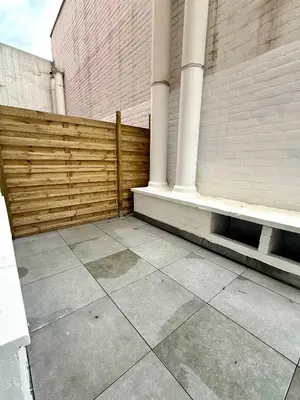 a patio with a wooden fence and a bench at Studio moderne au coeur du quartier Saint Adalbert in Liège