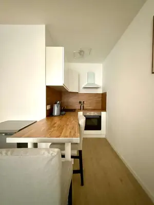 a kitchen with a table and white cabinets at Cosy studio en plein centre pour 2 personnes in Liège