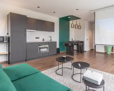 a living room with a green couch and a kitchen at Nomad Village in Verviers