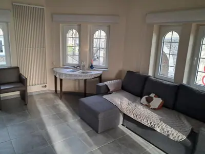 a living room with a couch and a table and windows at Domus moerenpoort in Tongeren