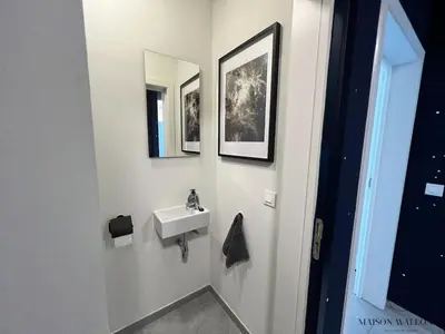 a bathroom with a sink and two pictures on the wall at La parenthèse céleste - 2 chambres & Sauna in Liège