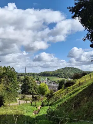 a bridge over a river with a grassy hill at Villa Bonifica in Riemst