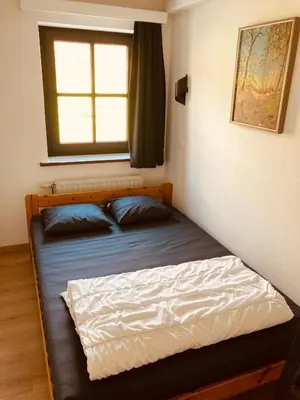 a bed in a small room with a window at De Molenhoeve Gezinswoning in Voeren