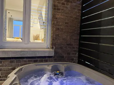 a jacuzzi tub in front of a window at Suite Luxueuse avec jaccuzi sans vis-à-vis in Liège