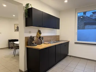 a kitchen with black cabinets and a sink at Suite Luxueuse avec jaccuzi sans vis-à-vis in Liège