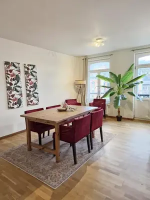a living room with a wooden table and red chairs at L'Horizon Saint-Lambert in Liège